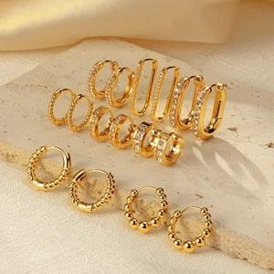 Elegant gold titanium steel hoop earring collection displayed on a premium textured stone surface