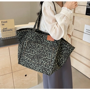 Close-up of leopard print canvas tote bag featuring brown leather patch and front pocket