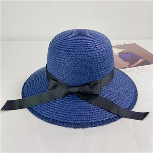 Flat lay of a navy straw hat with a black ribbon bow next to a magazine