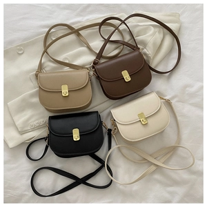 Flat lay of vintage saddle bags in khaki, brown, black, and white with gold metal buckles
