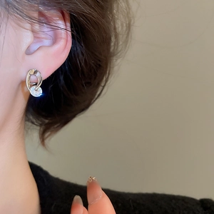 Detailed close-up showing twisted silver oval earrings with sparkling round zircon stone