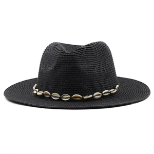 Close-up of black straw cowboy hat featuring cowrie shells and woven fedora texture