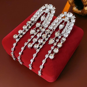 Detail of silver drop tassel earrings with sparkling rhinestones on red velvet