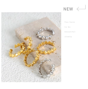 Macro shot of gold and silver wavy stackable rings on a textured stone display background