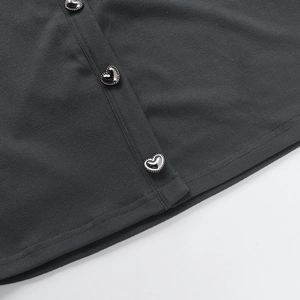 Détail du tissu en maille gris foncé avec des boutons métalliques argentés en forme de cœur