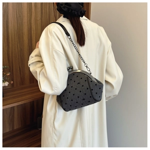 Detail of grey polka dot fabric shell bag worn with a chic cream trench coat