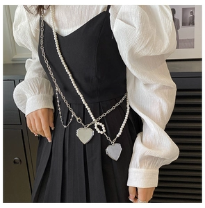 Detail of silver chain strap with white pearls and heart pendants on a stylish mini bag