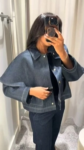 Detail der dunkelblauen Jeansjacke mit weißen Kontrastnähten und Metallknöpfen