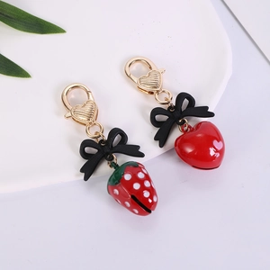 Detail of red strawberry and heart charms with golden lobster clasps and black bows