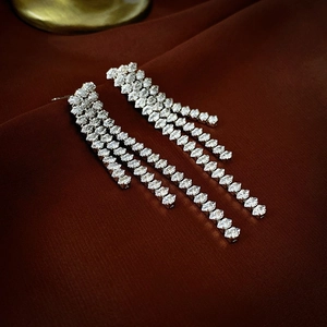 Macro detail of silver tassel earrings with sparkling crystals on dark velvet fabric