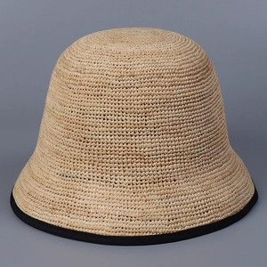 Detail of hand-woven raffia bucket hat featuring beige texture and black fabric trim