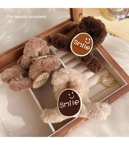 Detail of plush smile hair clips in brown and beige colors inside a wooden jewelry box