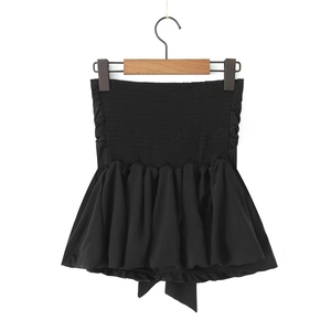 Detail of black strapless tube top featuring elastic smocked bodice and ruffled hemline