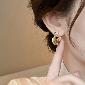 Detail view of a model wearing the gold twisted metal earring with elegant texture