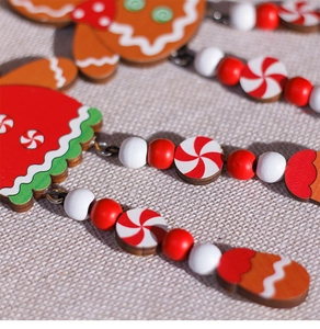 Close-up of wooden gingerbread man ornament with red painted beads for Christmas tree