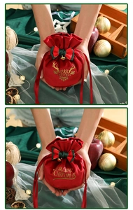 Detailed view of red velvet Christmas gift bags with gold Merry Christmas print and bows