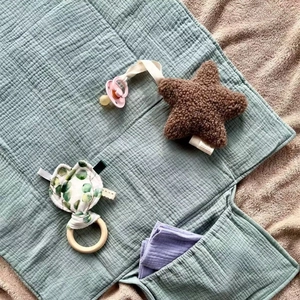 Sage green muslin baby changing mat with plush star pacifier clip and wooden teether