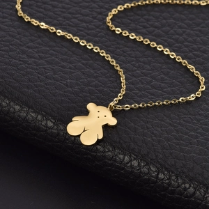Close-up of golden stainless steel necklace with bear pendant on black texture