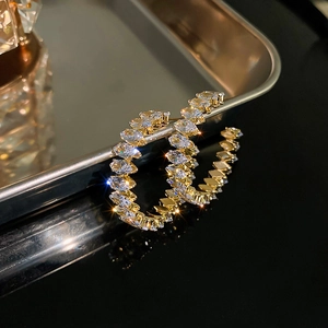 Macro detail of gold C-shaped hoop earrings with marquise-cut clear cubic zirconia crystals