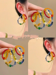 Detailed views of multi-colored beaded earrings in summer rainbow style on model and hand