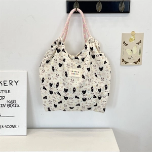 Close-up of cream canvas tote bag with cat and dog prints and pink woven handles