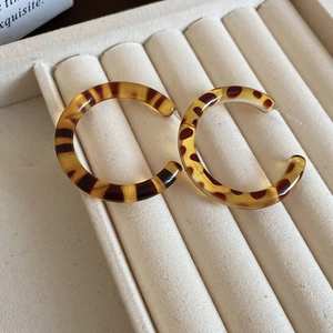 Detail of retro C-shaped resin earrings with leopard print in a beige velvet jewelry box