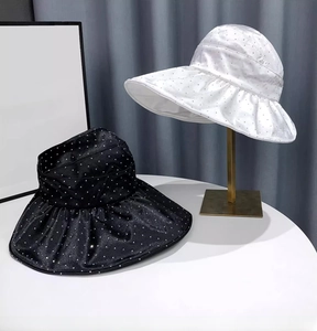 Detail of black and white sun hats with shimmering polka dots and wavy wide brims