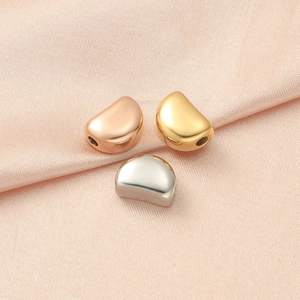 Polished stainless steel bead pendants in gold, silver, and rose gold on silk fabric