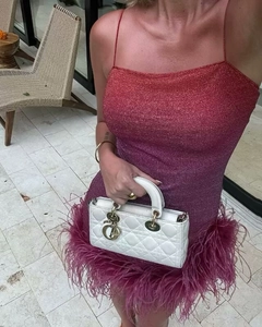Détail de la robe dégradée avec tissu brillant et bordure en plumes sur l'ourlet