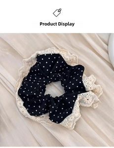 Detail of black polka dot silk scrunchie featuring elegant cream lace edging texture