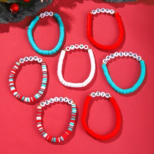 Detail of Christmas beaded bracelets with Merry and Joy charms on red textured surface