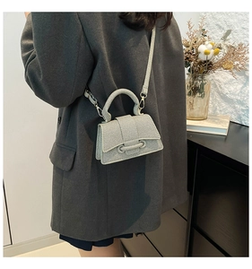 Détail du sac bandoulière gris à rayures avec base incurvée et rabat à nœud décoratif