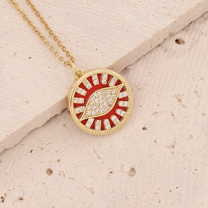 18K gold plated copper necklace with zircon evil eye pendant on a beige stone surface