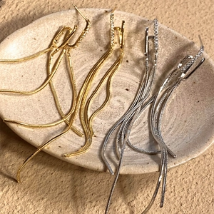 Close-up of elegant gold and silver tassel earrings with zircon studs on ceramic plate