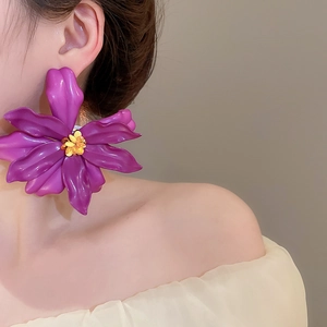 Macro side view of large purple acrylic flower earrings with yellow beaded centers on a model