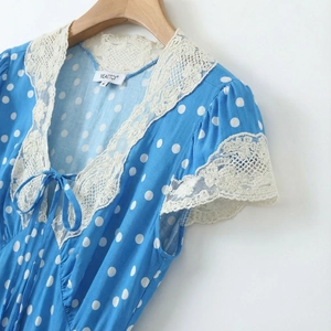 Close-up of sky blue polka dot dress with delicate lace collar and bow tie detail
