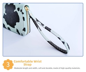 Detail of a light blue cow print long wallet showing smooth zipper and wristlet strap