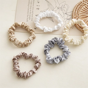 Detailed close-up of 5-piece silk satin scrunchies in neutral elegant color tones