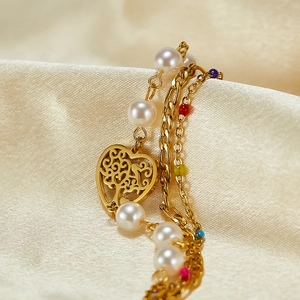 Detail view of double-layer gold chain bracelet with pearls and hollow heart charm