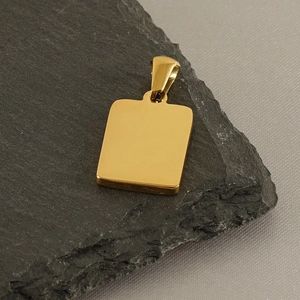 Detailed view of polished 18k gold plated rectangular pendant on textured stone