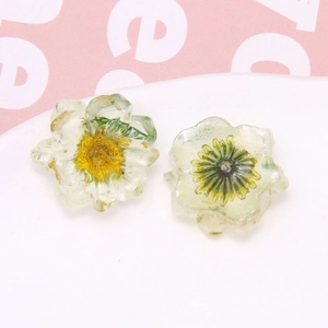 Detail shot of clear resin flower charms with embedded yellow and green dried petals