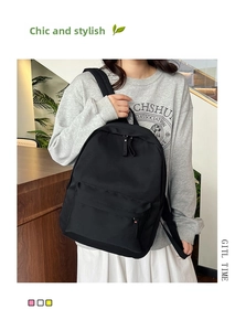 Detail of lightweight black canvas backpack featuring a large front zipper pocket and strap