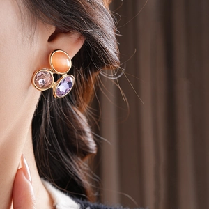Detail showing vintage oval earrings with orange, pink, and purple cat eye gemstones