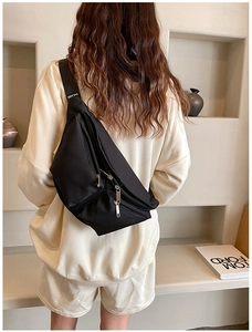Detail view of the black crossbody chest bag with adjustable wide straps on a model