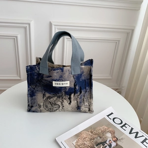 Detail of canvas lunch bag featuring blue ink marble pattern and woven handles