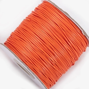 Detailed macro view of vibrant orange waxed polyester cord on a roll for jewelry making