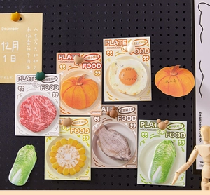 Flat lay of food-shaped sticky notes with realistic steak, egg, and vegetable designs