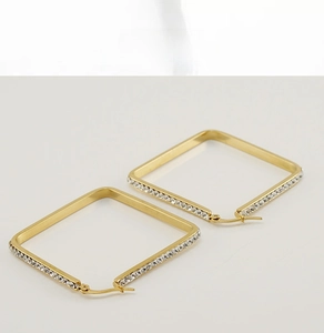 Detail of square gold earrings featuring minimalist geometric design and sparkling zircon inlay
