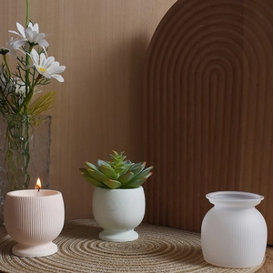 Detailed view of striped candle holders and succulent pots on a natural straw mat