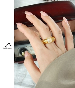 Close-up of golden stainless steel ring with rectangular glass stone on a model's finger